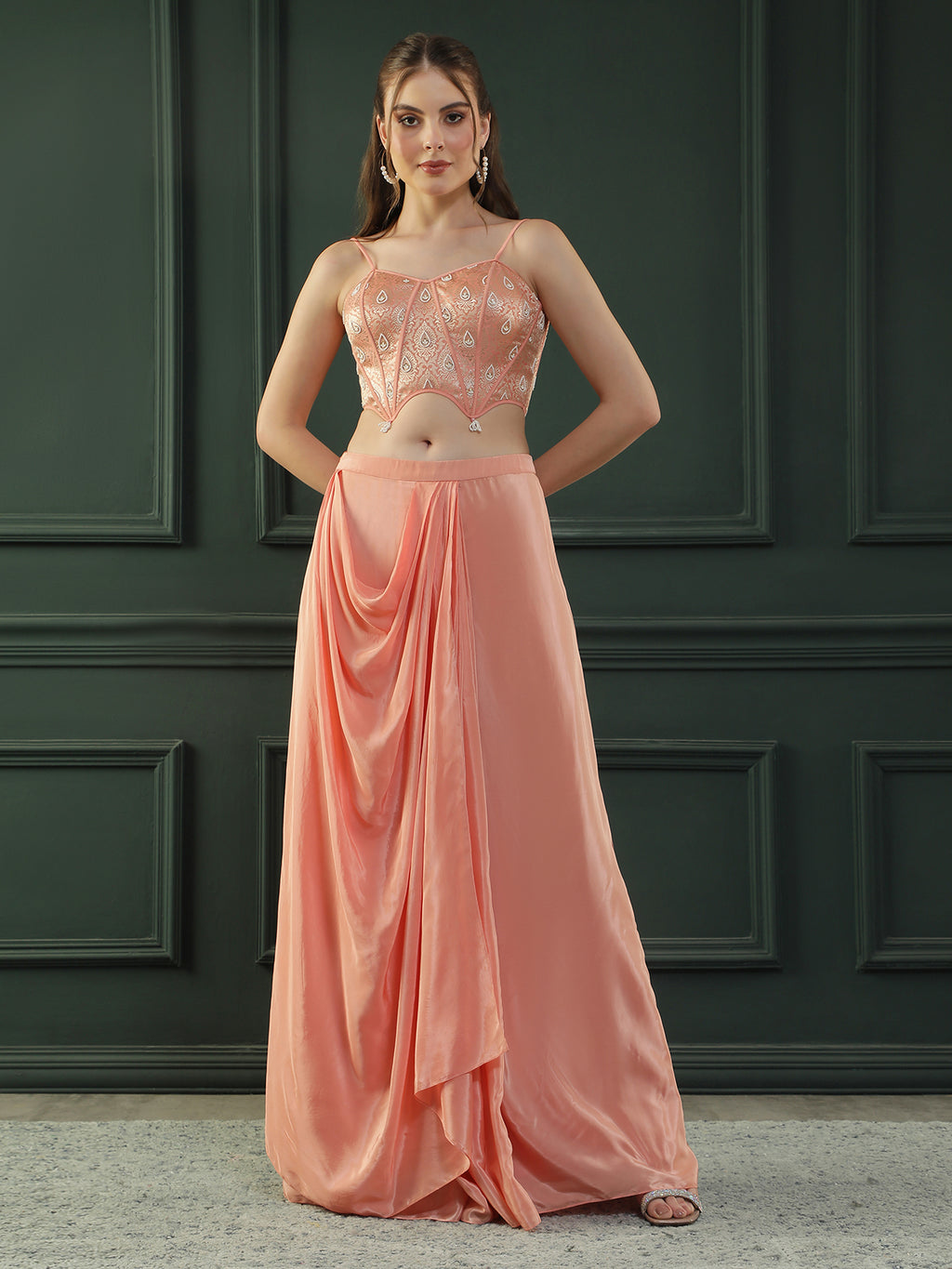 Peach drape skirt paired with brocade corset with a hand-embellished pearl highlight and plain dupatta with latkans drop on its sides.