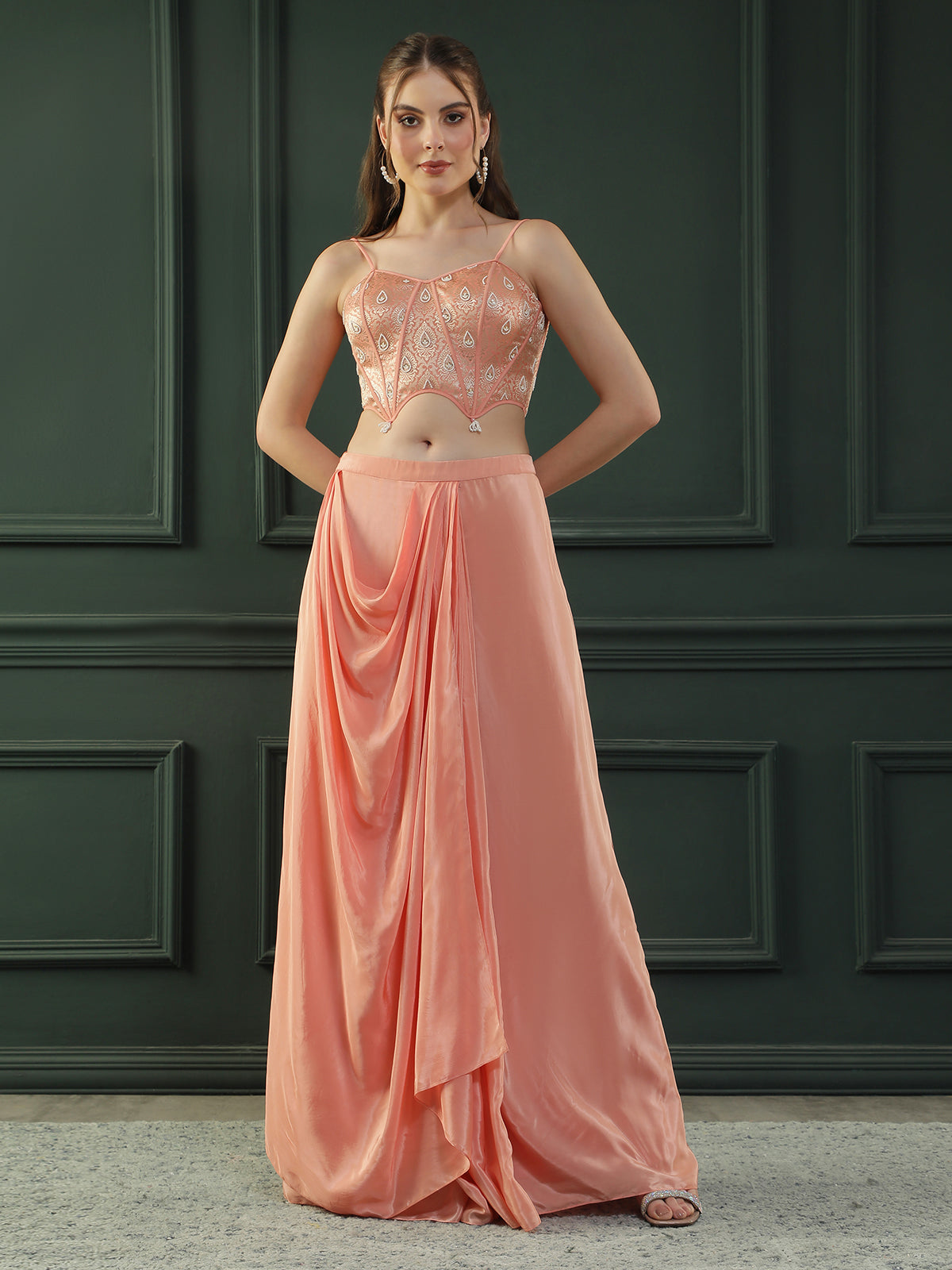 Peach drape skirt paired with brocade corset with a hand-embellished pearl highlight and plain dupatta with latkans drop on its sides.