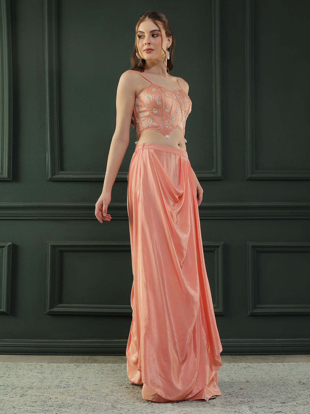 Peach drape skirt paired with brocade corset with a hand-embellished pearl highlight and plain dupatta with latkans drop on its sides.