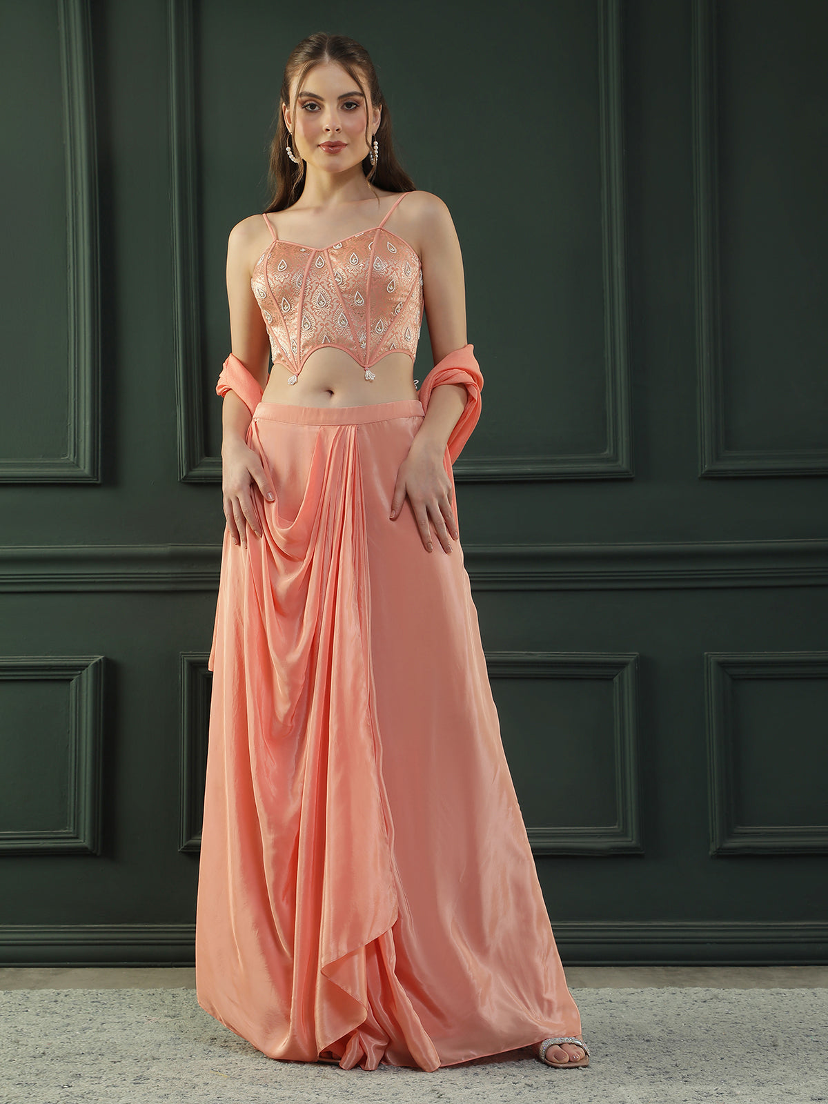 Peach drape skirt paired with brocade corset with a hand-embellished pearl highlight and plain dupatta with latkans drop on its sides.