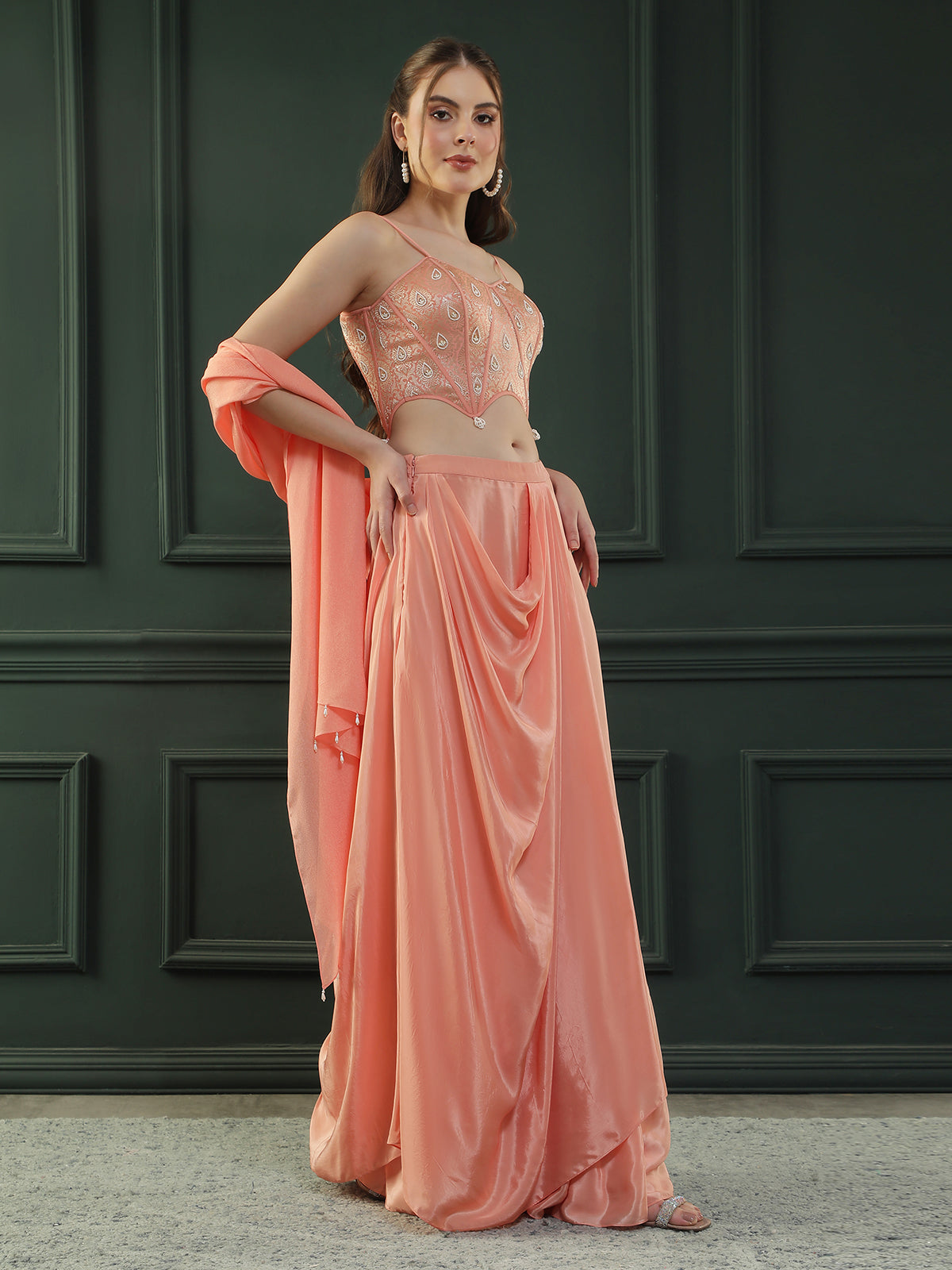Peach drape skirt paired with brocade corset with a hand-embellished pearl highlight and plain dupatta with latkans drop on its sides.