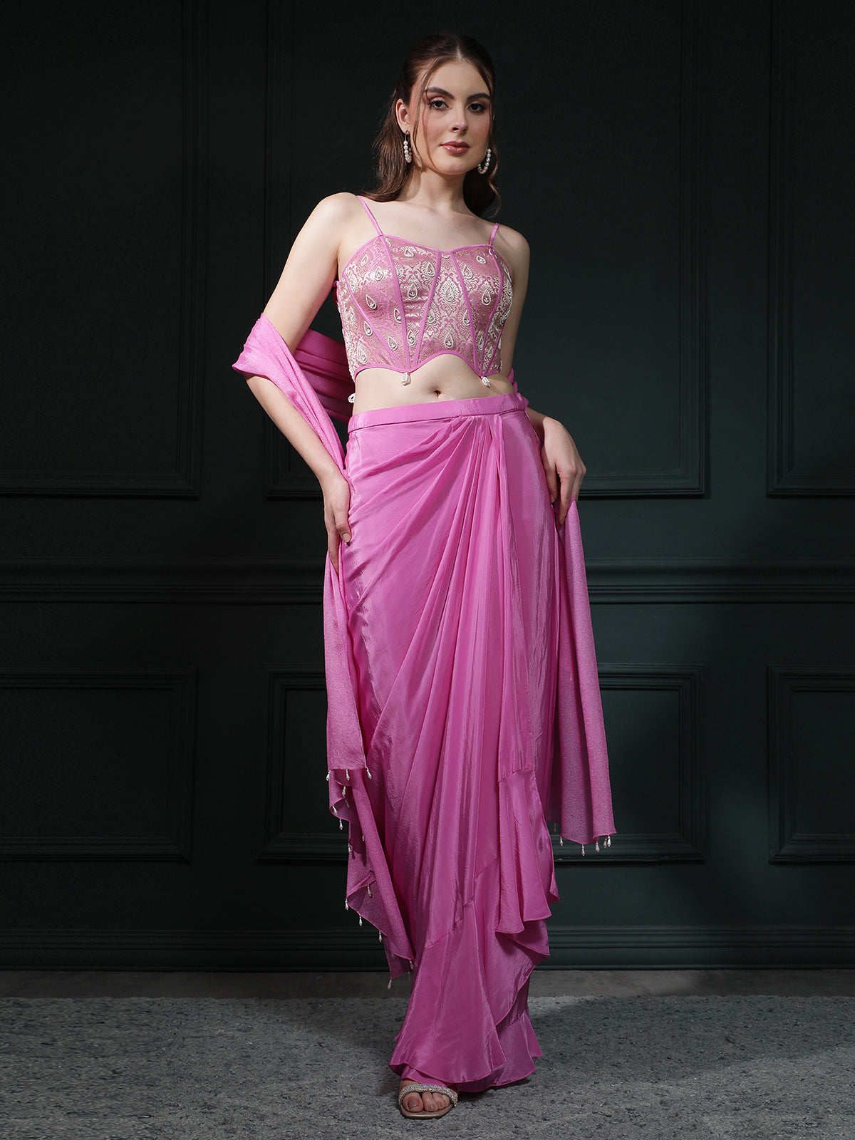 Fuscia Pink crepe drape skirt paired with brocade corset with a hand-embellished pearl highlight and plain dupatta with latkans drop on its sides.