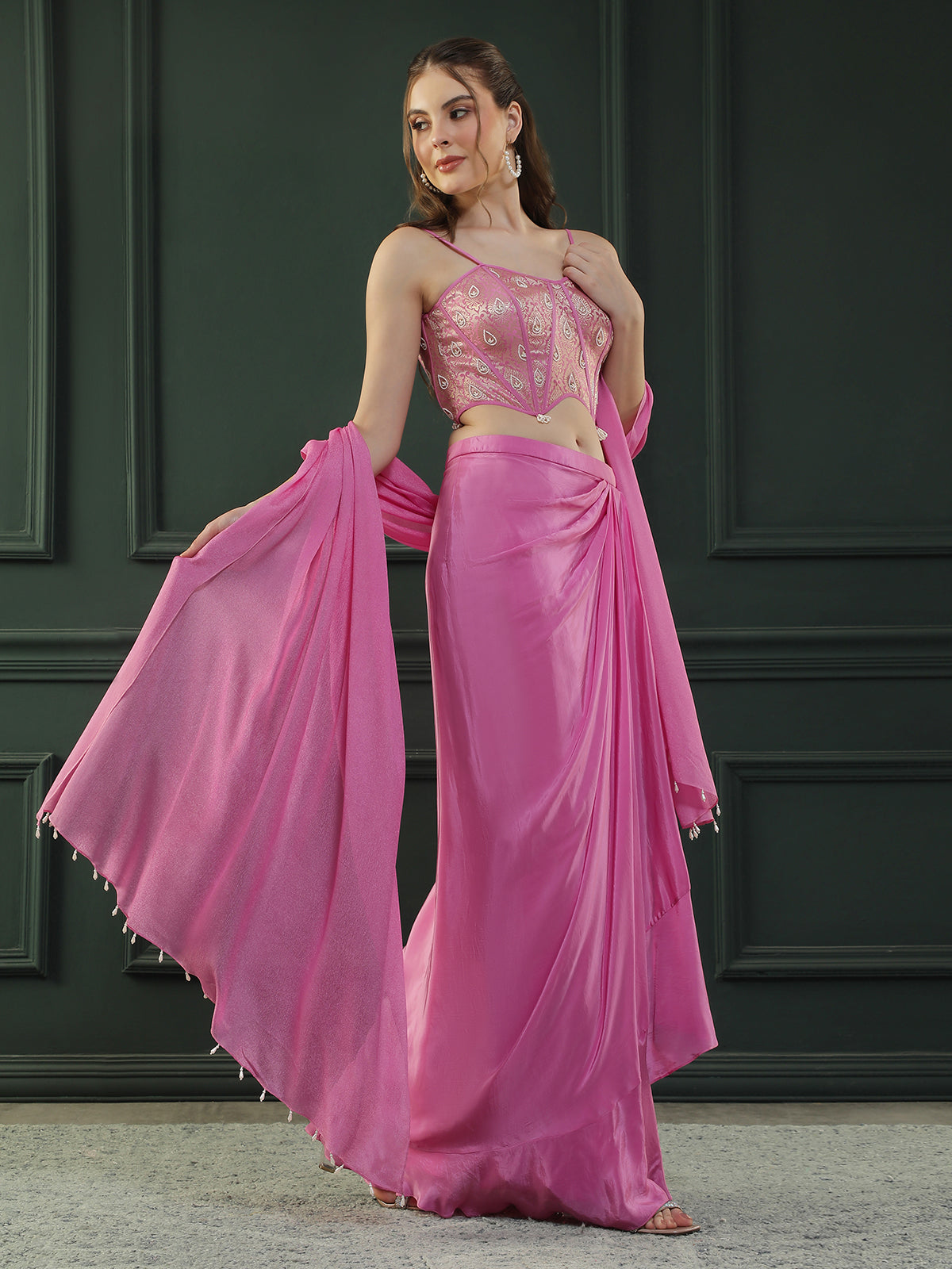 Fuscia Pink crepe drape skirt paired with brocade corset with a hand-embellished pearl highlight and plain dupatta with latkans drop on its sides.