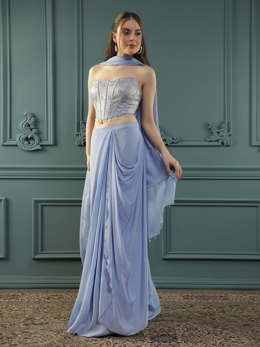 Lilac drape skirt paired with brocade corset with a hand-embellished pearl highlight and plain dupatta with latkans drop on its sides.