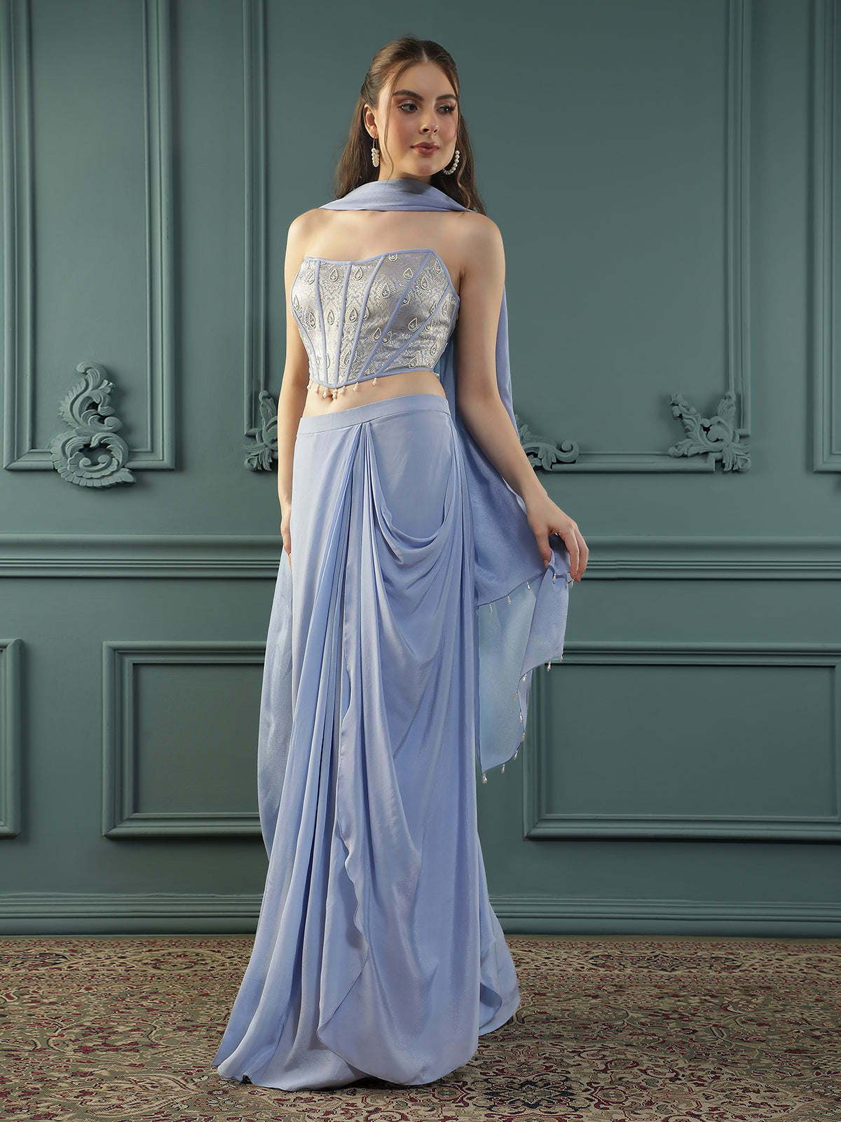 Lilac drape skirt paired with brocade corset with a hand-embellished pearl highlight and plain dupatta with latkans drop on its sides.