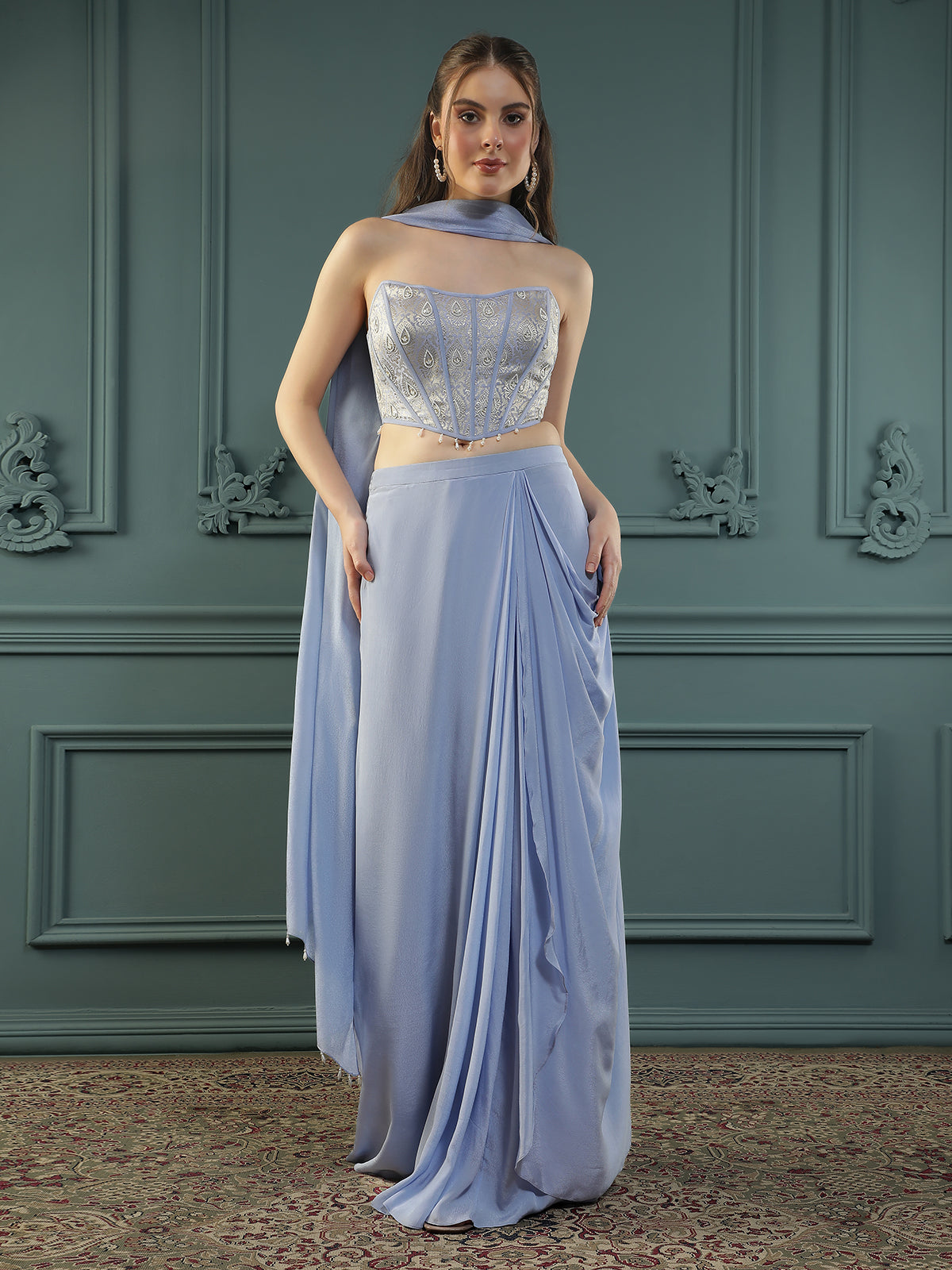 Lilac drape skirt paired with brocade corset with a hand-embellished pearl highlight and plain dupatta with latkans drop on its sides.