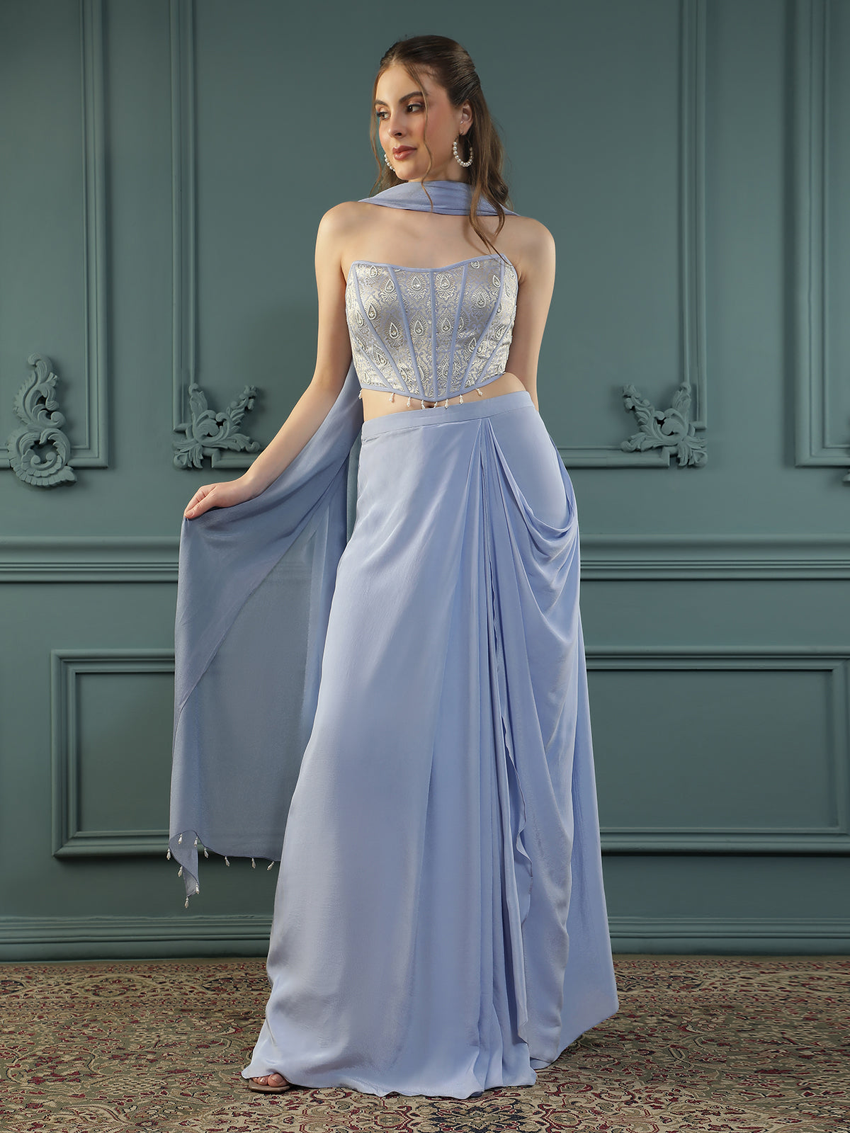 Lilac drape skirt paired with brocade corset with a hand-embellished pearl highlight and plain dupatta with latkans drop on its sides.
