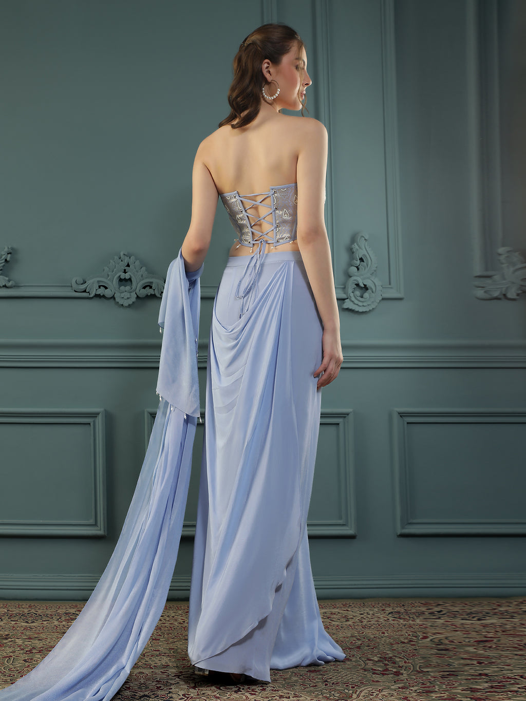 Lilac drape skirt paired with brocade corset with a hand-embellished pearl highlight and plain dupatta with latkans drop on its sides.