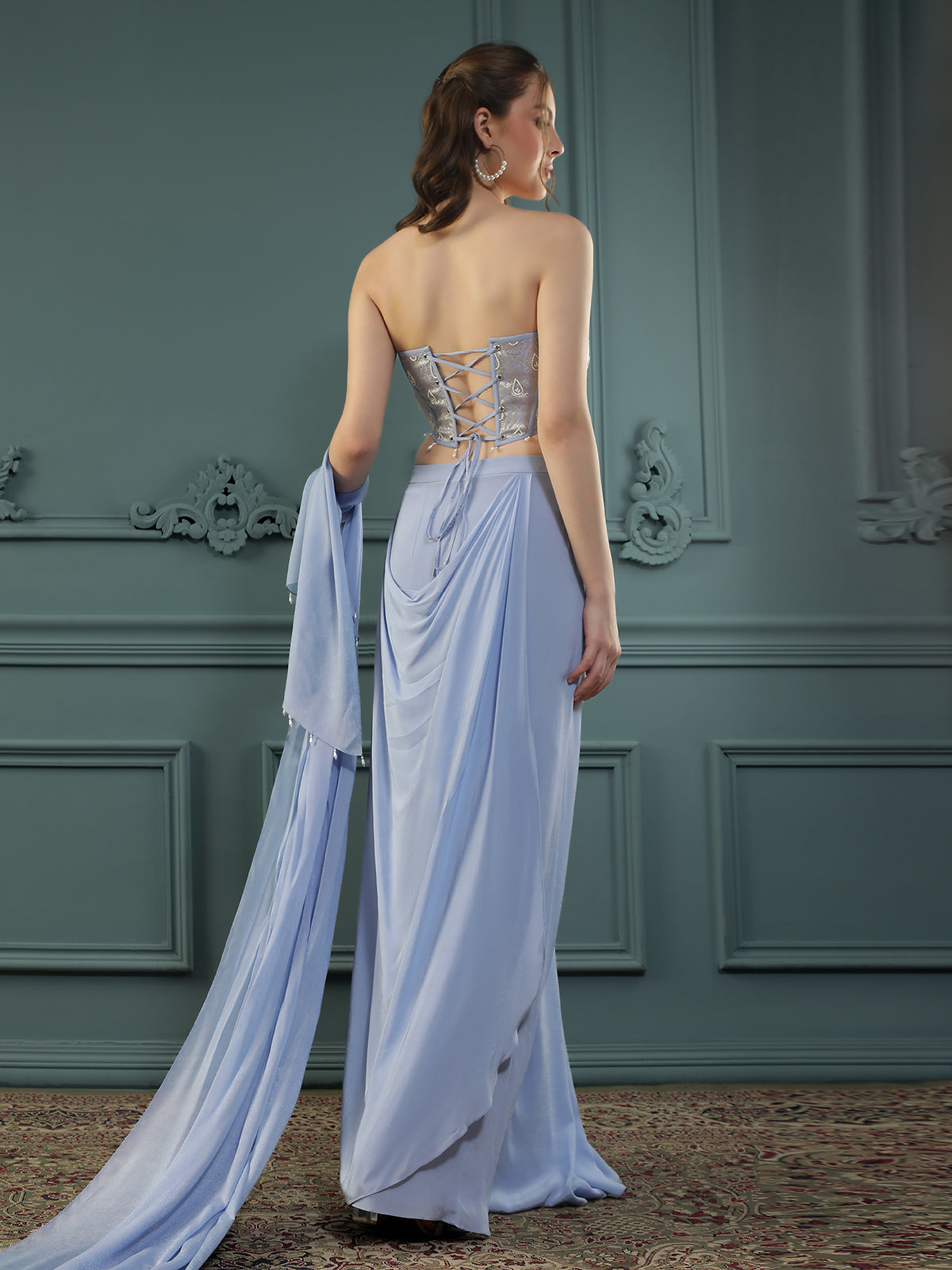Lilac drape skirt paired with brocade corset with a hand-embellished pearl highlight and plain dupatta with latkans drop on its sides.