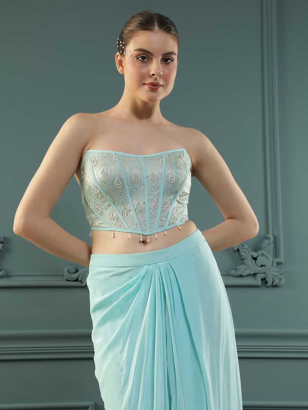 Ice-Blue drape skirt paired with brocade corset with a hand-embellished pearl highlight and plain dupatta with latkans drop on its sides.
