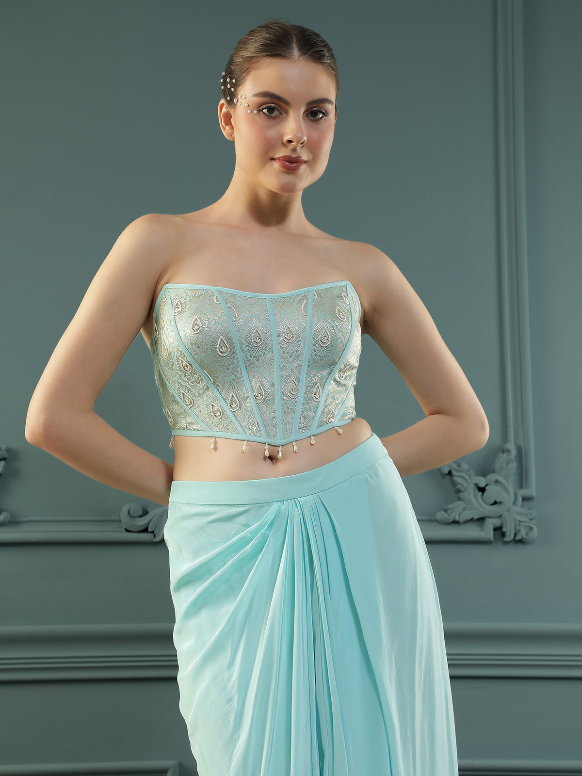 Ice-Blue drape skirt paired with brocade corset with a hand-embellished pearl highlight and plain dupatta with latkans drop on its sides.