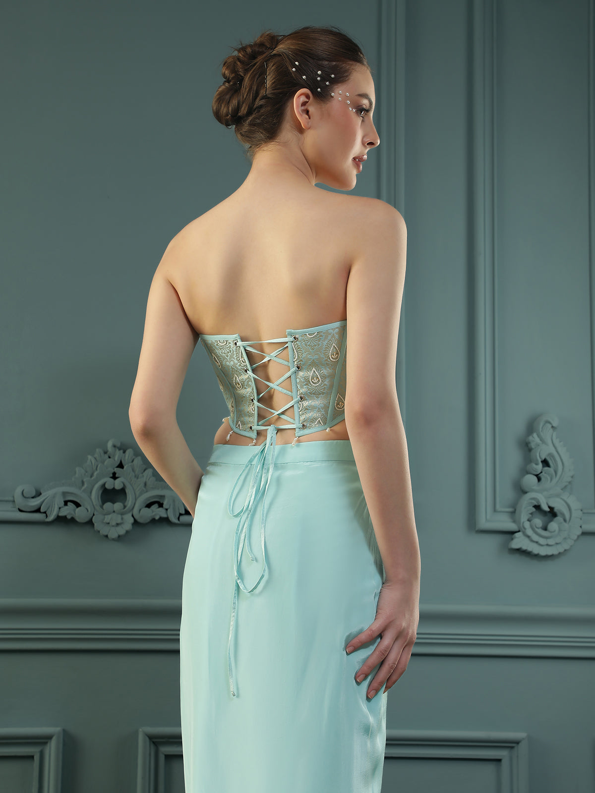 Ice-Blue drape skirt paired with brocade corset with a hand-embellished pearl highlight and plain dupatta with latkans drop on its sides.