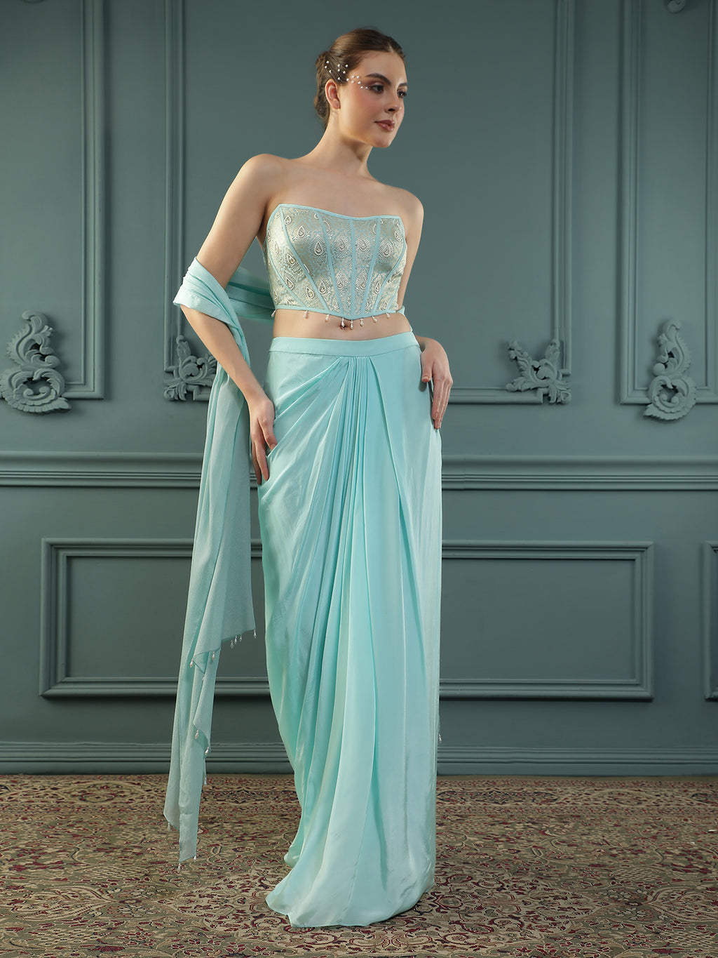 Ice-Blue drape skirt paired with brocade corset with a hand-embellished pearl highlight and plain dupatta with latkans drop on its sides.